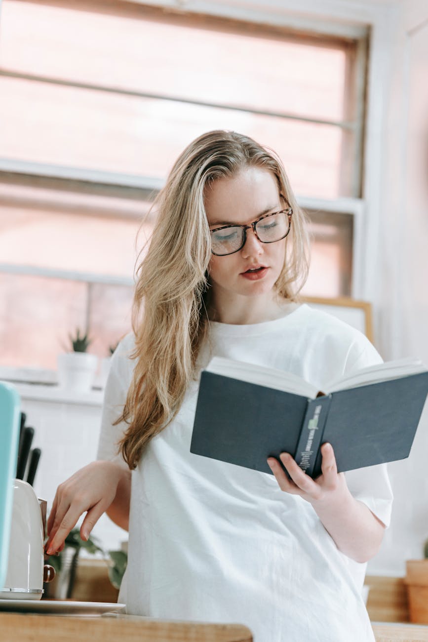 focused woman reading book in kitchen